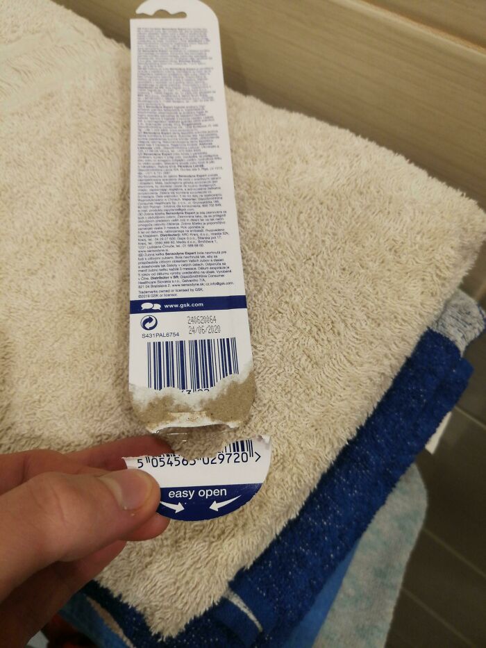 A hand holding a piece of ripped packaging, part of the 87 People Who Are Having A Way Worse Day Than You.