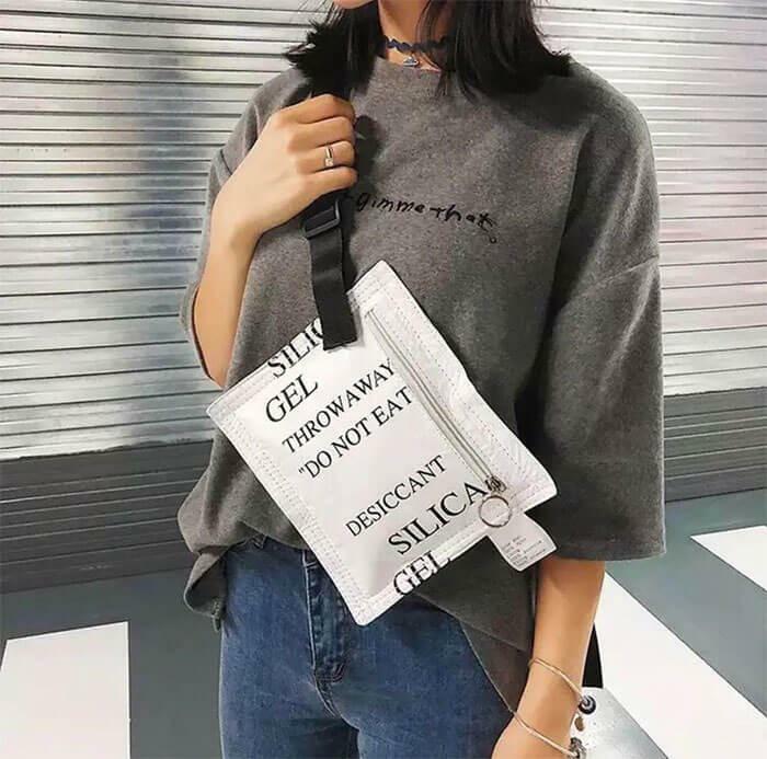 A woman carries a crossbody bag designed to look like a large silica gel packet, a brilliant transformation of ordinary things.