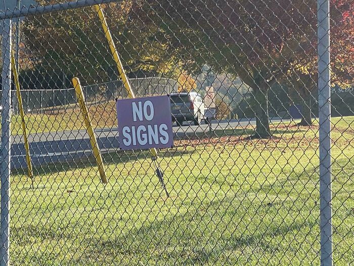 A sign on a fence hilariously failed by reading NO SIGNS, humorously contradicting itself.