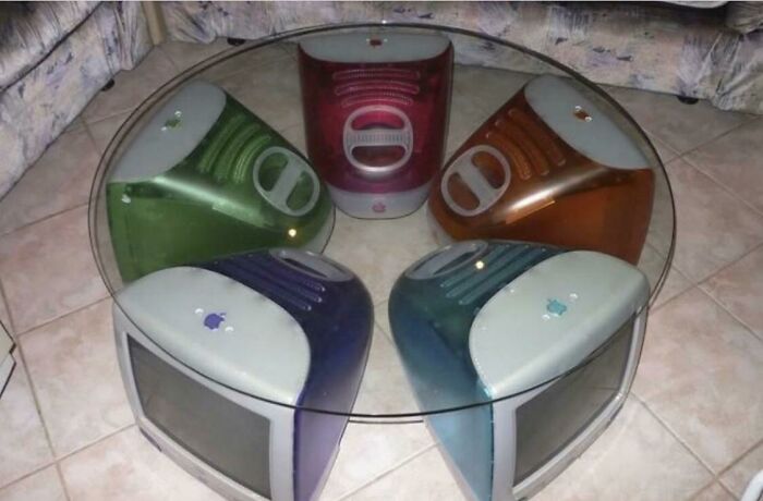 A glass coffee table supported by five colorful iMac G3 computers, showcasing designers transforming ordinary things.