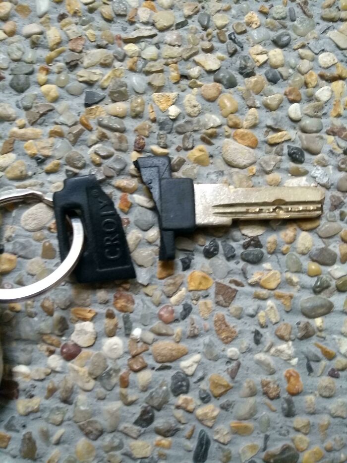 A broken key on a keychain lying on a stone surface, having a worse day than you.