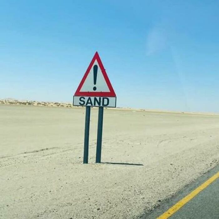A hilariously failed sign warns of sand in the middle of a vast desert with sand everywhere.