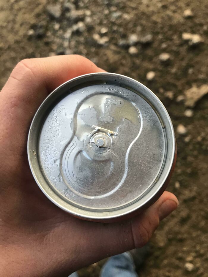 A hand holds a soda can with a broken tab, having a worse day than you.