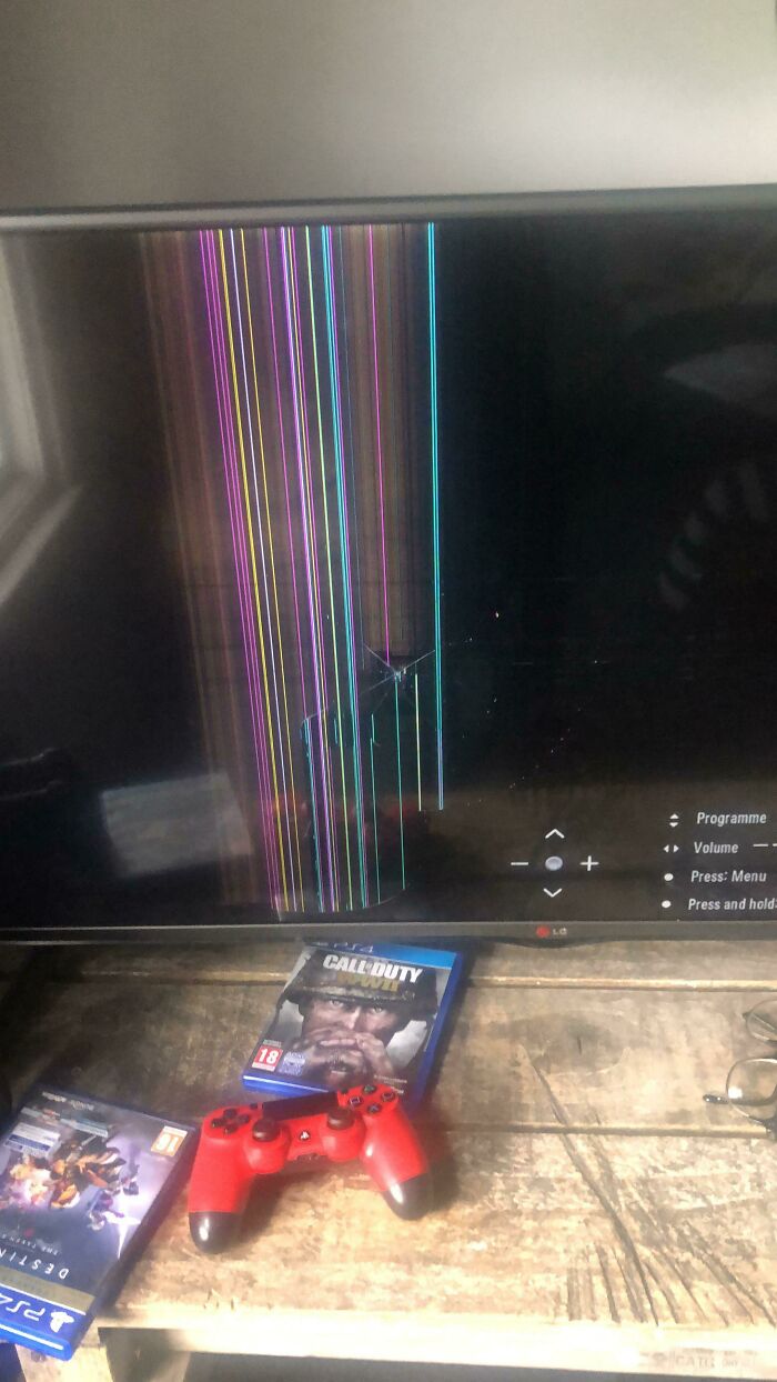 A cracked TV screen with colorful vertical lines and video games below, depicting people having a worse day.