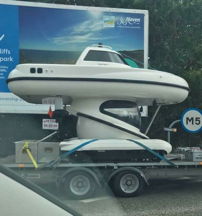 A futuristic white boat-like vehicle on a trailer, an ordinary thing brilliantly transformed for transport.
