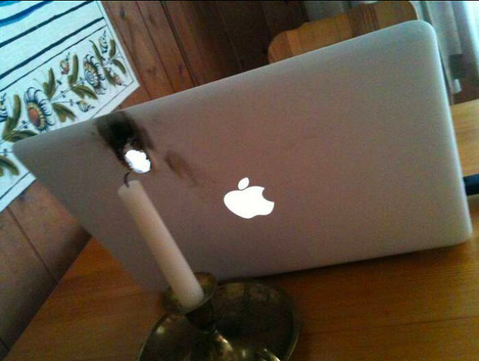 A burned laptop with a candle next to it, illustrating a person having a worse day.