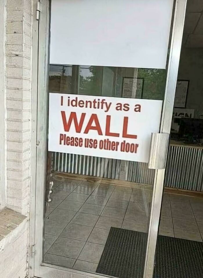 A hilariously failed sign on a glass door that reads I identify as a WALL, Please use other door.