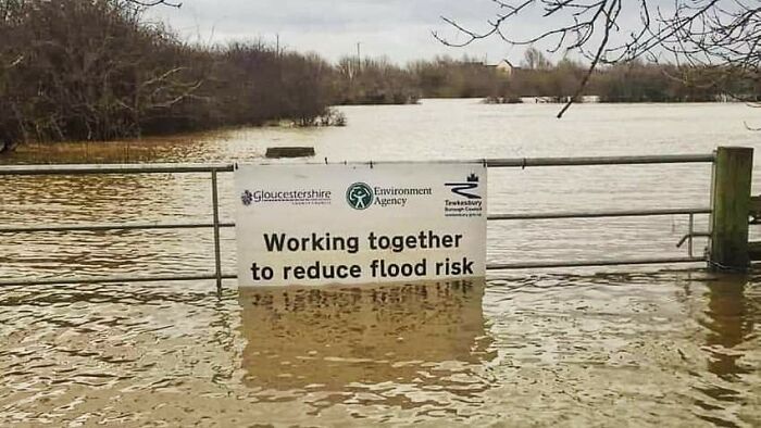 A sign promoting flood risk reduction submerged in floodwaters, a hilarious sign failure.