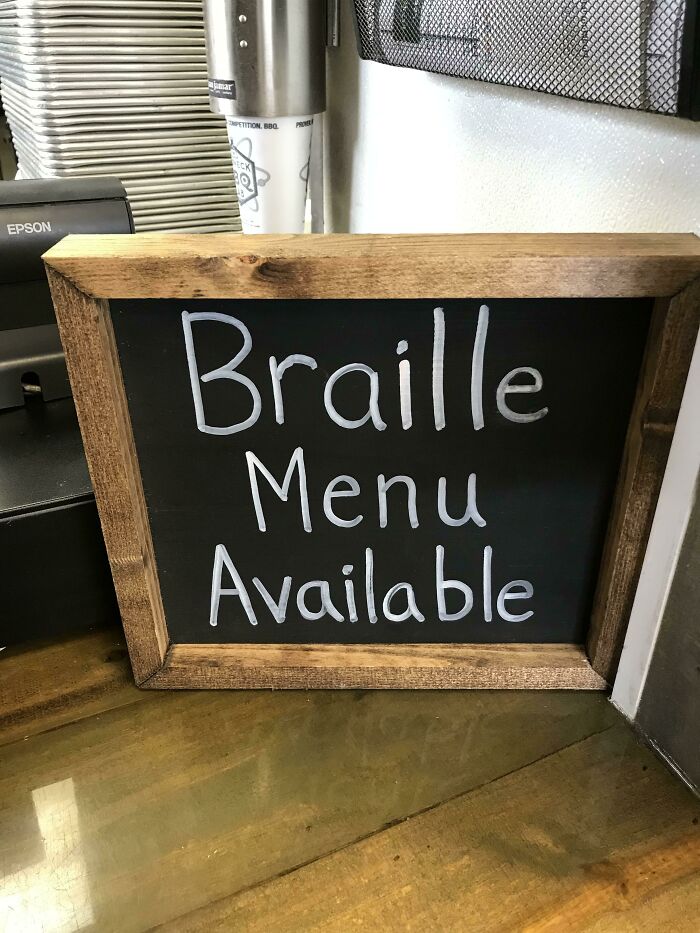 A chalkboard sign states Braille Menu Available, but is written in print, a hilariously failed sign.