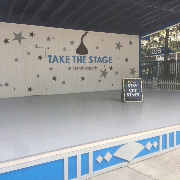 A sign at Hersheypark reads Take the Stage, but a smaller sign below says Please Stay Off Stage, a hilariously failed sign.