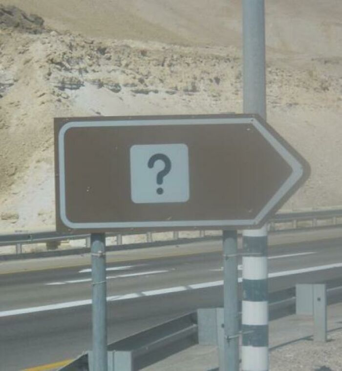 A brown road sign with a question mark on it, hilariously failed at providing direction.