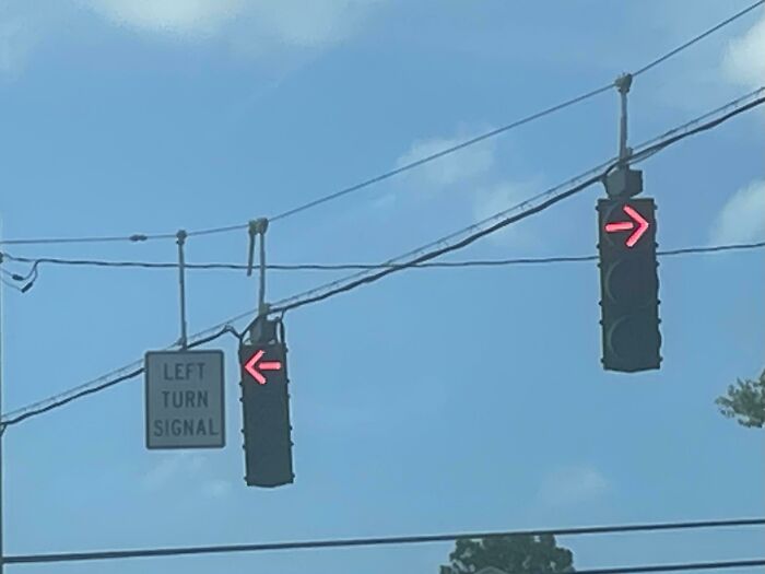 A traffic signal and left turn sign with conflicting arrows, a hilariously failed sign.