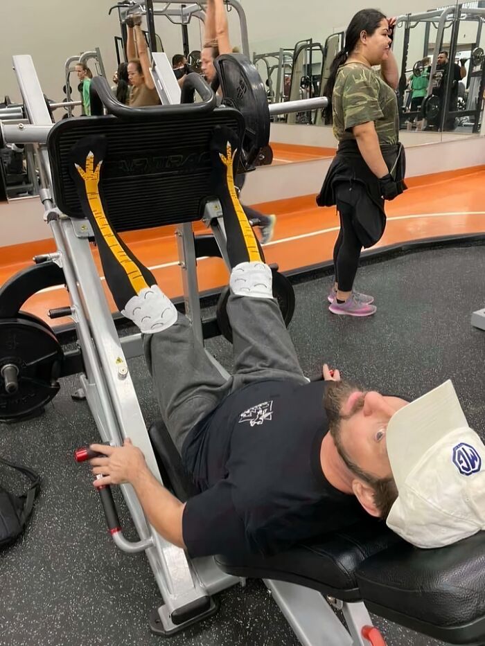 A man wearing chicken leg socks on a leg press machine, transforming an ordinary gym workout into an enjoyable moment.