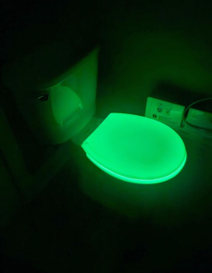 A glowing green toilet seat in the dark, showcasing brilliantly transformed ordinary things by designers.