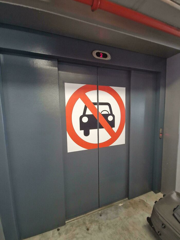 A hilariously failed sign on an elevator door showing a no-car symbol.