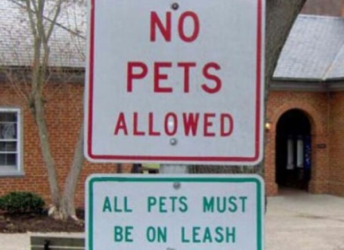 Two conflicting signs: one says NO PETS ALLOWED, the other ALL PETS MUST BE ON LEASH. A sign that hilariously failed.