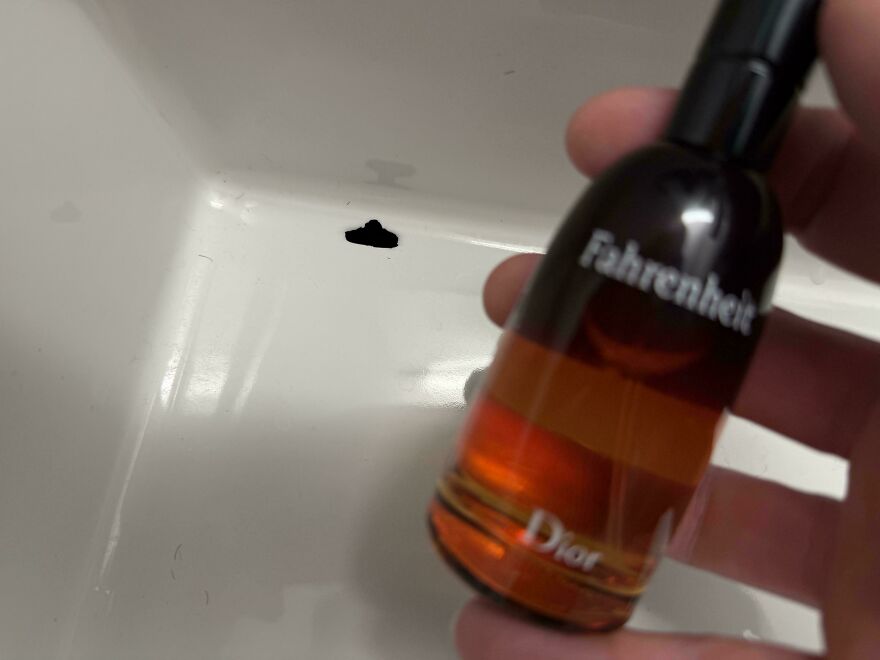 A small bottle of Dior Fahrenheit cologne held over a sink with a black stain, an expensive mistake.