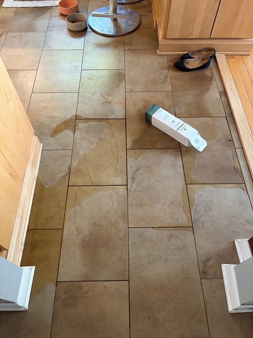 A kitchen floor with spilled liquid from a fallen box, a household expensive mistake causing a mess.