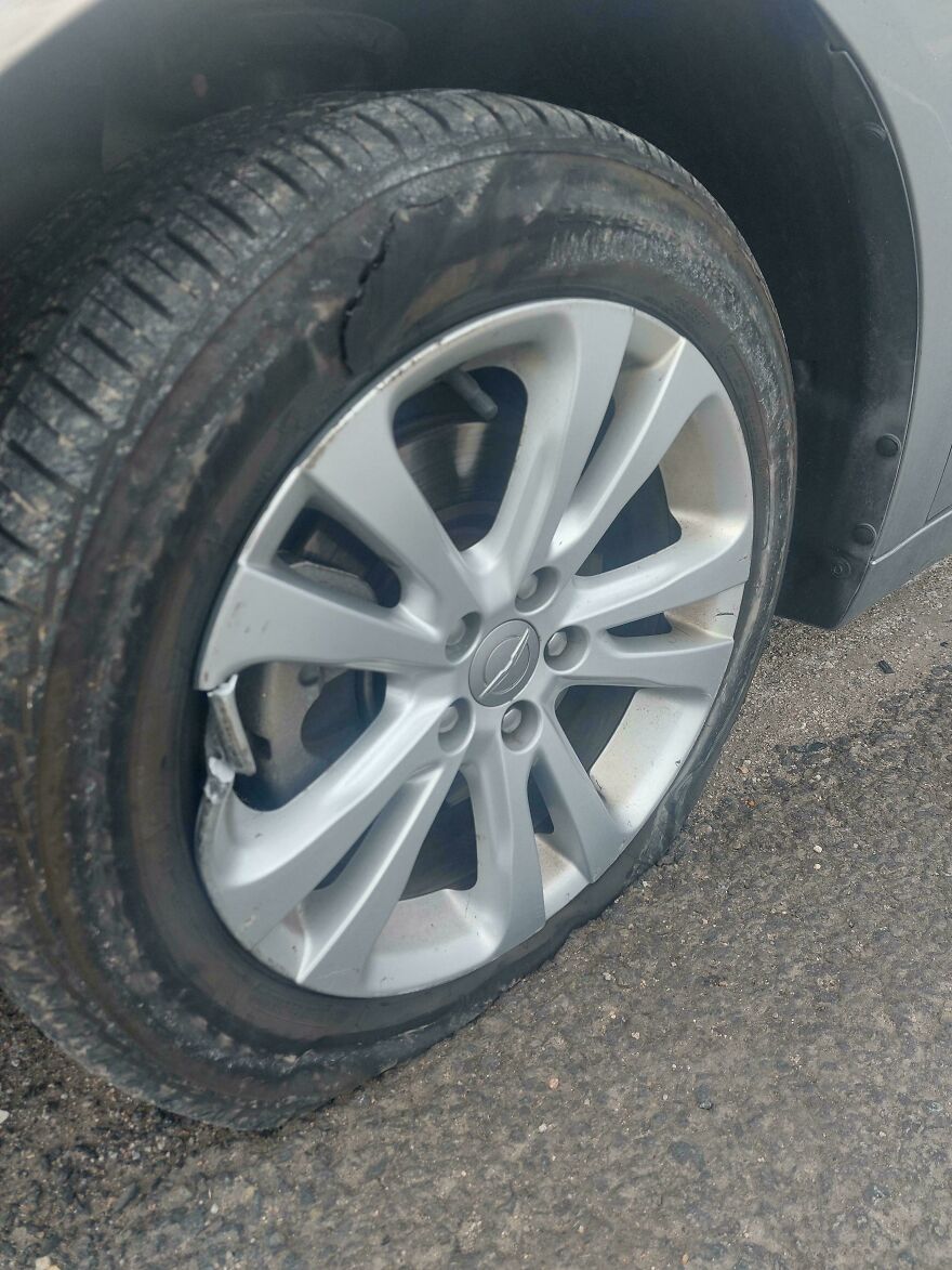 A car wheel with a completely flat tire and damaged rim, an expensive accident requiring repair.