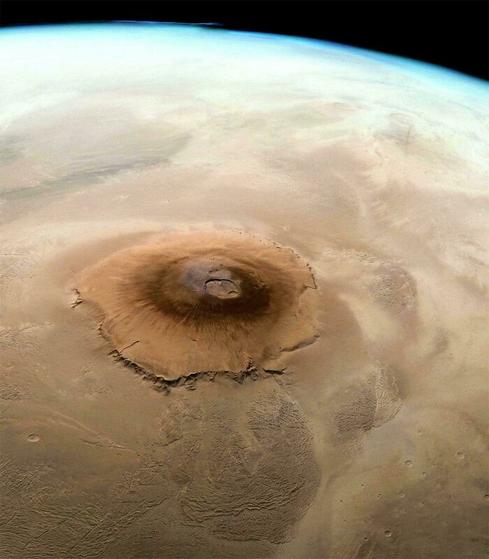 An aerial view of a large desert mountain on Mars, offering a true scale of its immense size.
