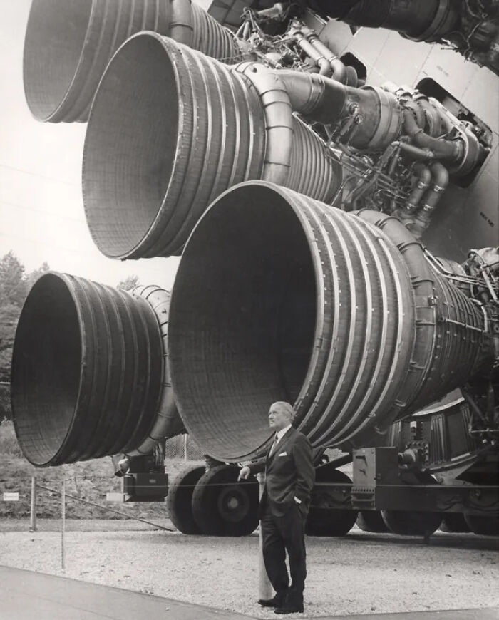 A man standing next to massive rocket engines, providing a size comparison that highlights their true scale.