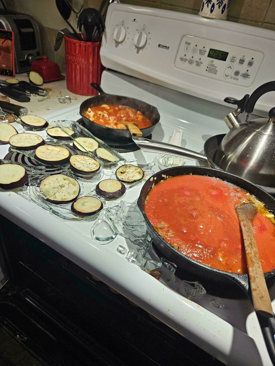 Eggplant slices and sauce on a stovetop with shattered glass, a messy and expensive mistake or accident.
