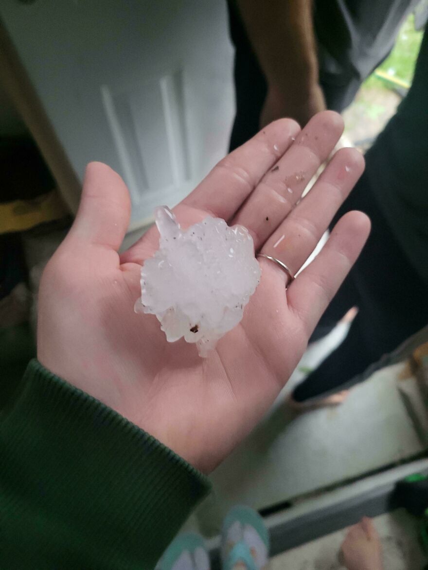 An expensive mistake: A hand holding a large, jagged piece of hail, indicating a potential weather accident.