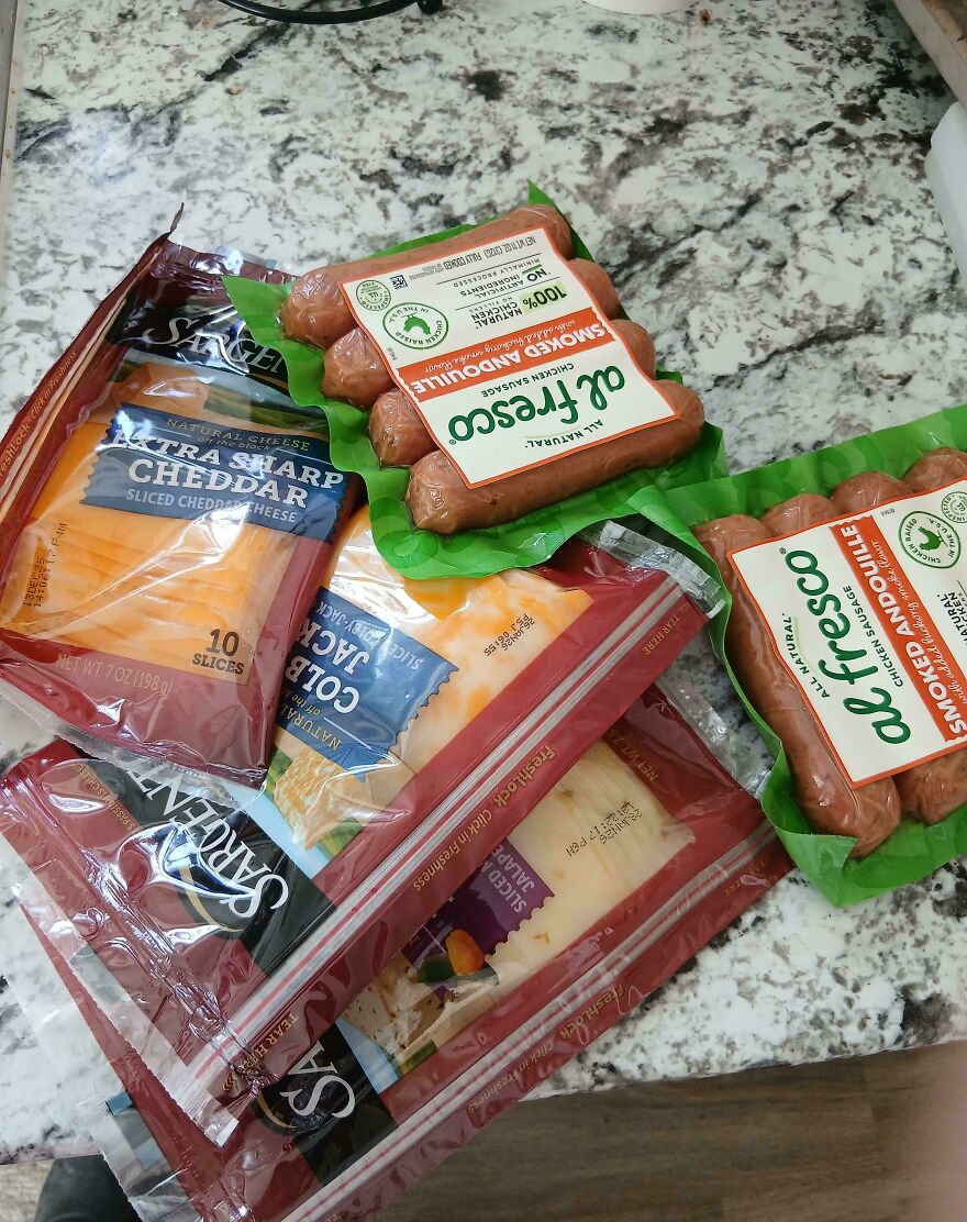 Various packages of sliced cheese and smoked sausage on a kitchen counter, an expensive mistake and accident.