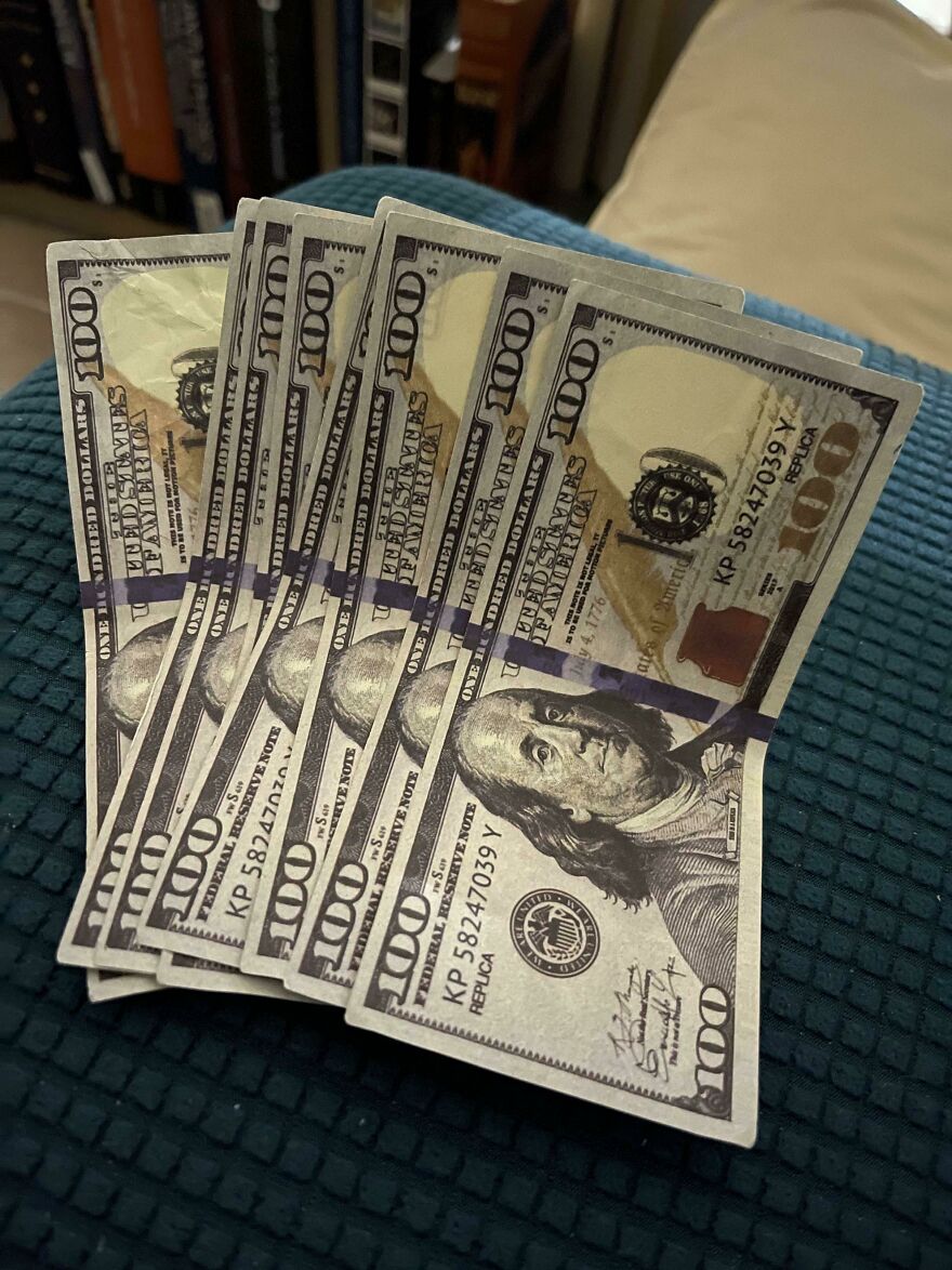 Several fake hundred-dollar bills, clearly marked replica, lie on a textured surface, an example of expensive mistakes.
