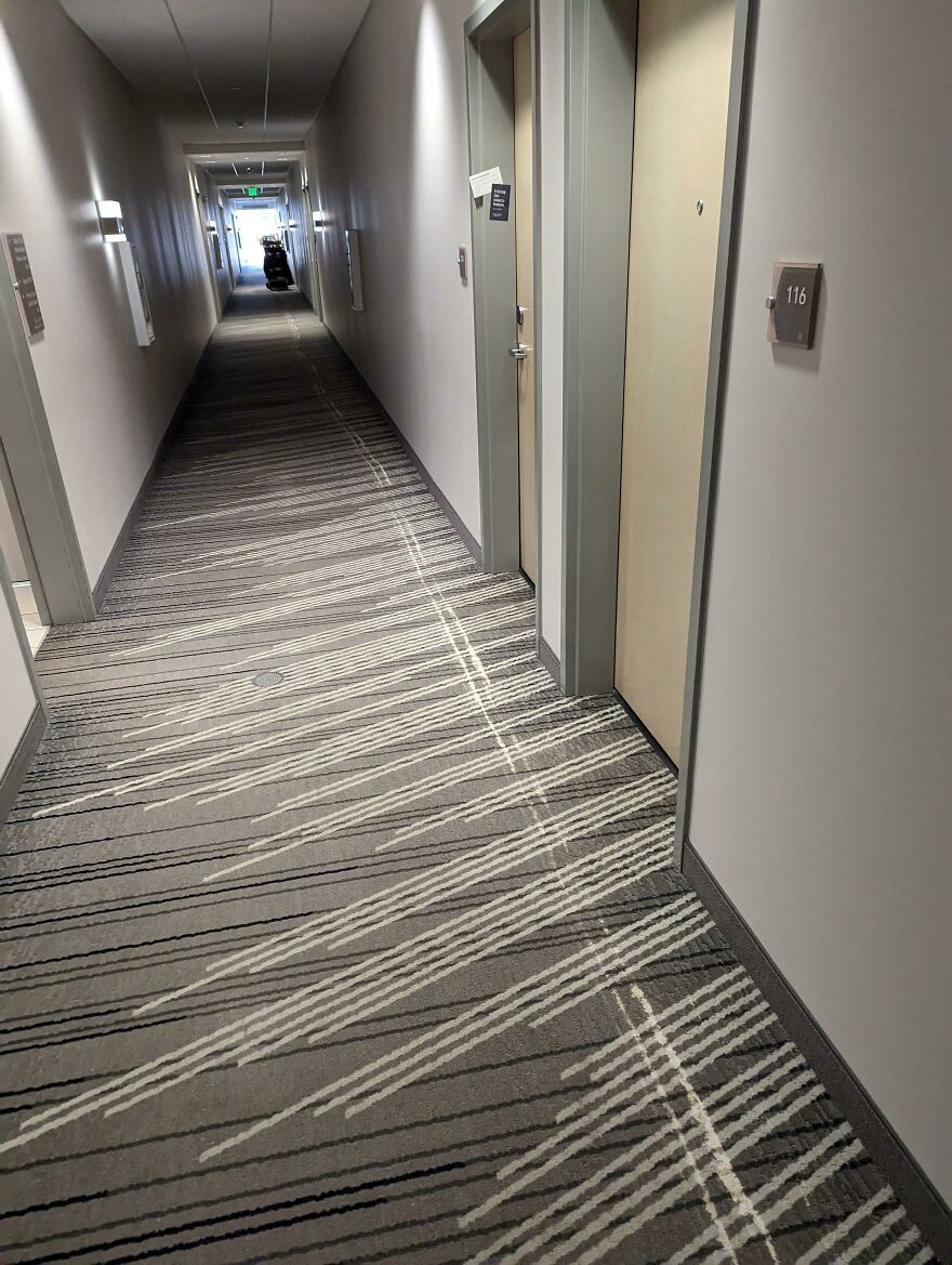 A long hotel hallway with patterned carpet, showing an expensive mistake in design and potential accident area.
