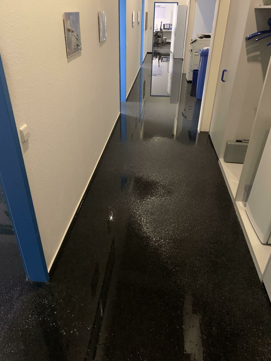 A hallway with a black, shiny floor reflecting light, revealing an expensive mistake of a significant water leak or flood.