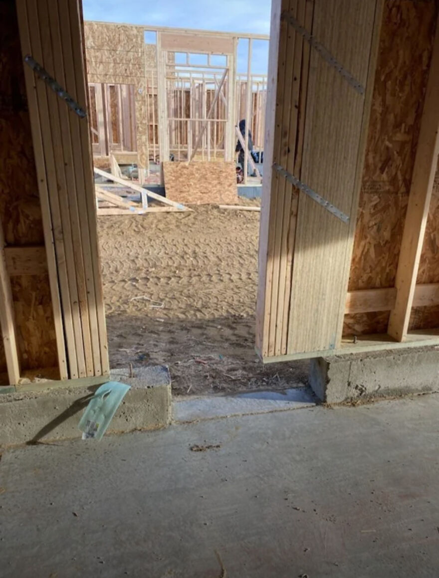 An incomplete building frame with exposed wooden studs, revealing an expensive mistake in construction with a missing foundation step.