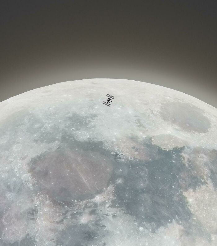 The International Space Station (ISS) in orbit above the moon, providing a dramatic size comparison.