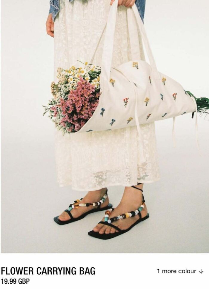 A person carries flowers in a white Zara website bizarre content bag, wearing a lace dress and beaded sandals.