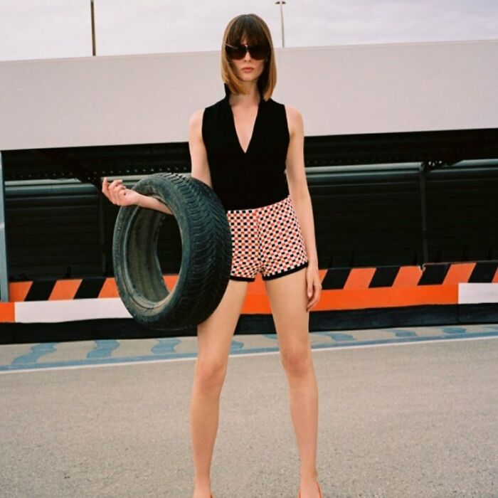 A woman in sunglasses and shorts holding a tire, presenting bizarre content on the Zara website.