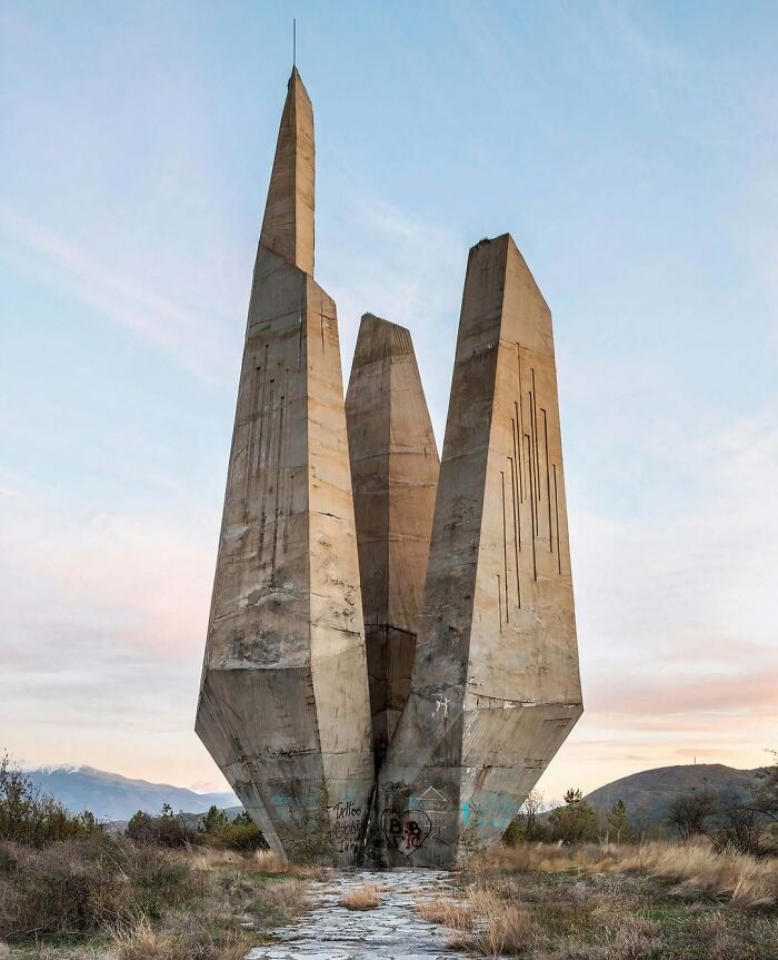 A brutalist concrete monument with sharp angles and tall spires under a cloudy sky, showcasing brilliant design choices.