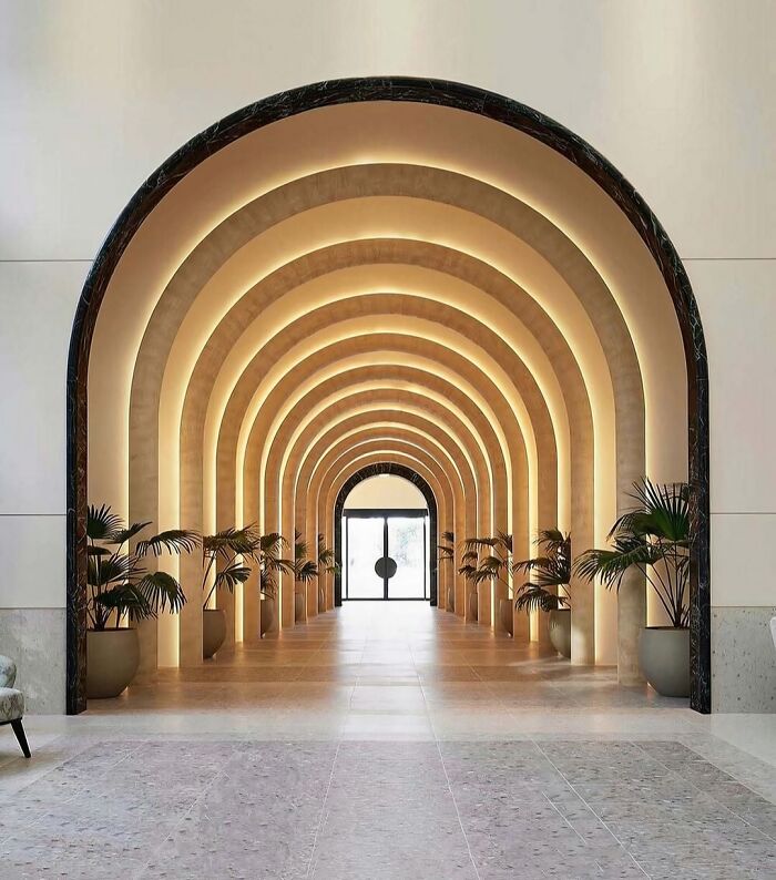 A brilliant design choice with a hallway featuring illuminated arches and potted plants, creating a stunning visual effect.