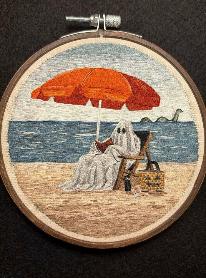 Embroidery project featuring a ghost reading on a beach chair under an orange umbrella