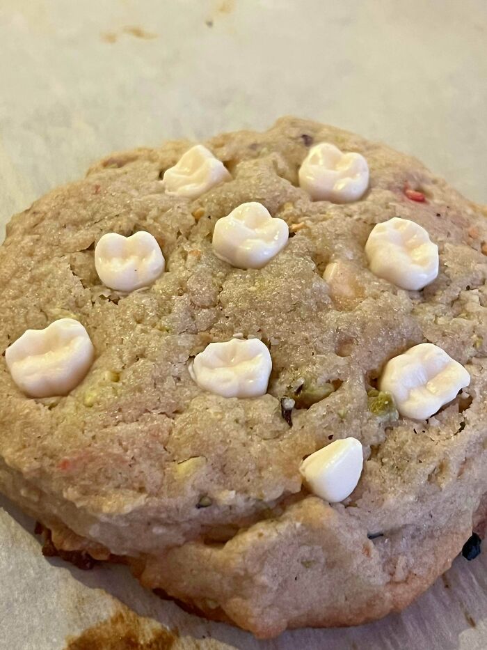 A close-up of a large cookie topped with white chocolate chips, a delicious treat from bakers.
