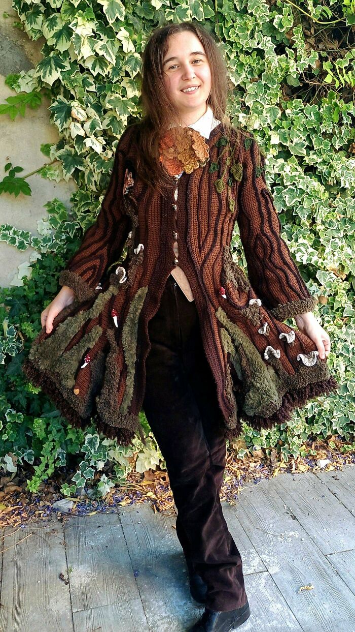 Creative crochet coat with mushrooms and leafy motifs worn by a smiling woman outdoors