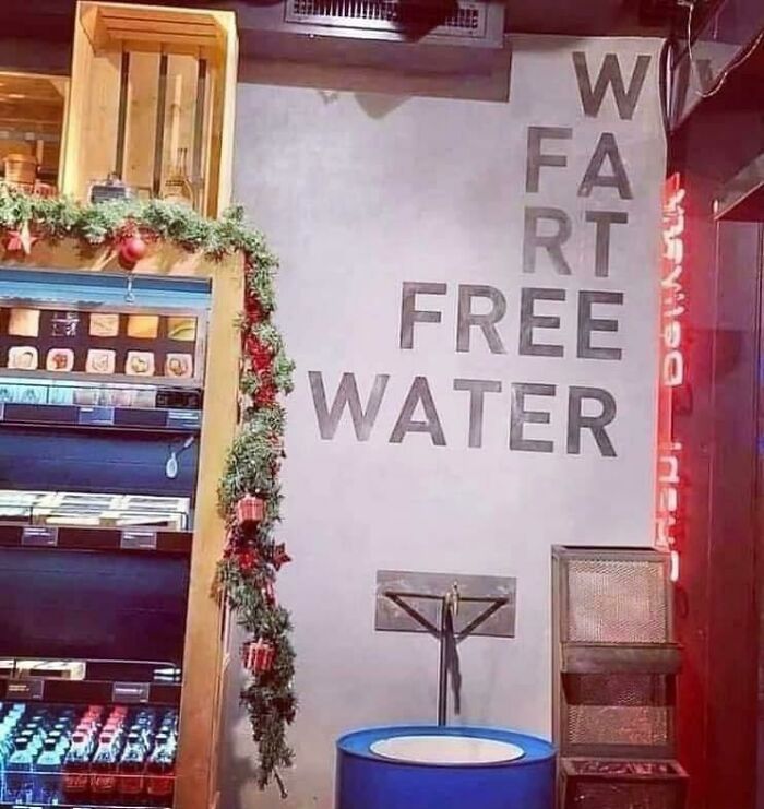 A hilariously awful design fail with a sign that reads W FART FREE WATER, next to a store display with garland.