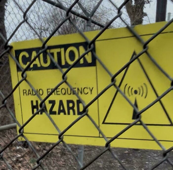 A caution sign on a chain-link fence warns of a radio frequency hazard, an unexpected find for urban explorers.