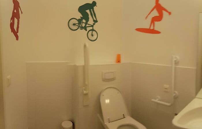 A hilariously awful design fail: a toilet with extreme sports decals like biking and surfing above it.