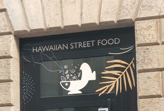 A hilariously awful design fail: a Hawaiian street food sign with an odd fish bowl graphic and a palm leaf.