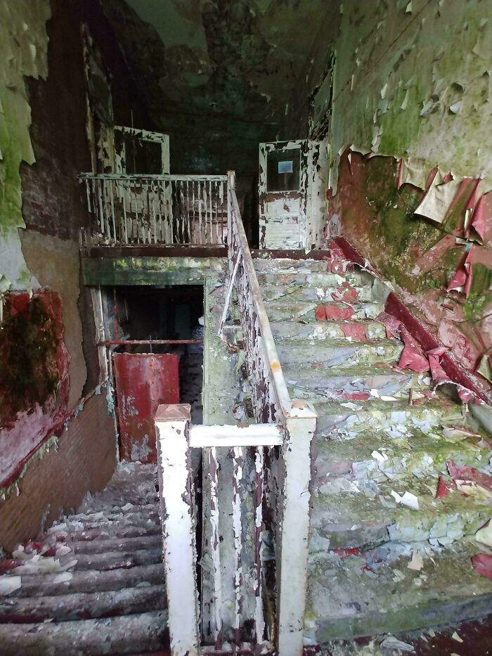 An old, abandoned building interior with peeling paint on walls and stairs, showcasing an unexpected find for urban explorers.