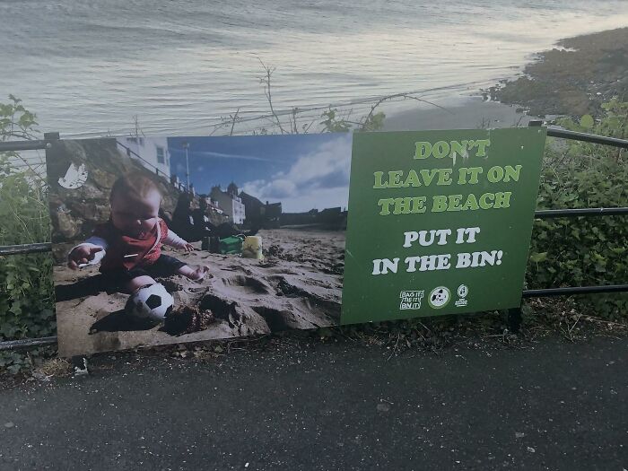 A beach sign with a baby playing in the sand, next to text that is an awful design fail.