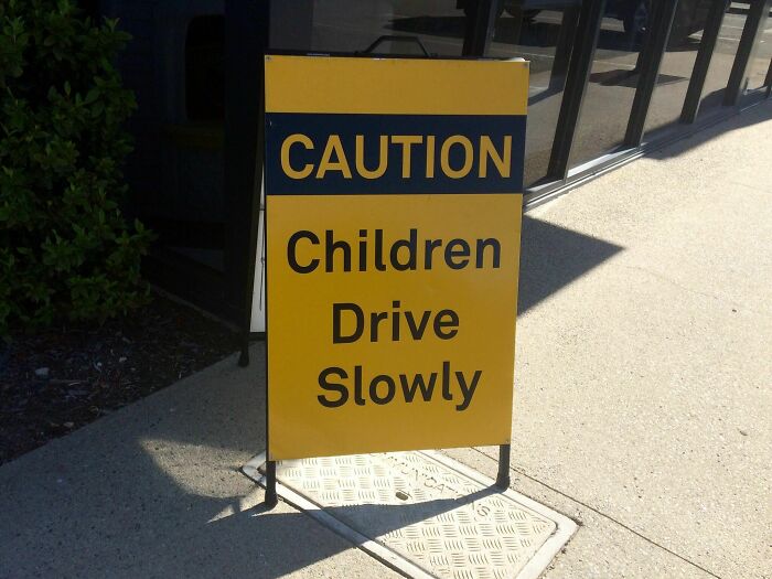 A sign with an awful design fail: CAUTION CHILDREN DRIVE SLOWLY, meaning children are driving.
