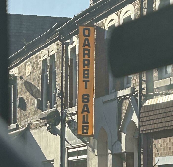 A vertical orange sign on a brick building that reads GARRET SALE instead of CARPET SALE, an awful design fail.