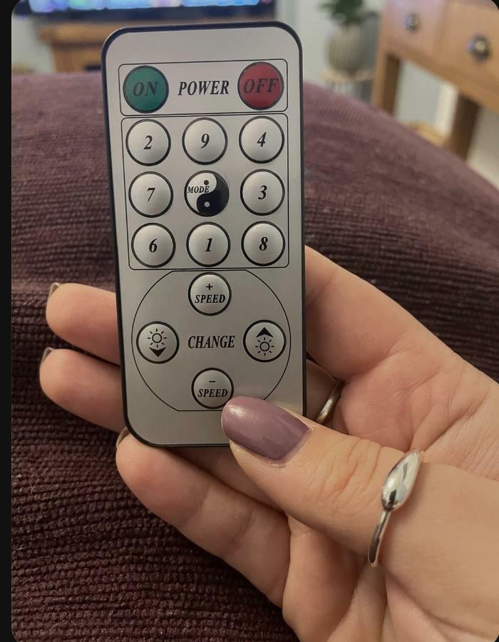 A hand holding a remote control with a confusing layout, an awful design fail.