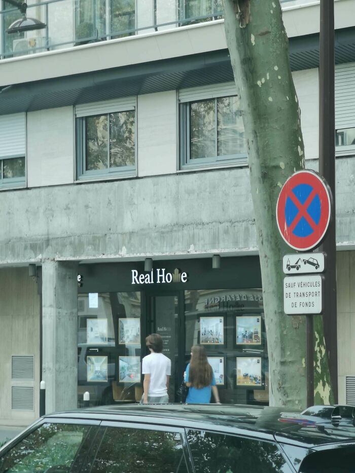 A sign in front of a real estate office with a partially obscured name showing a hilarious awful design fail.